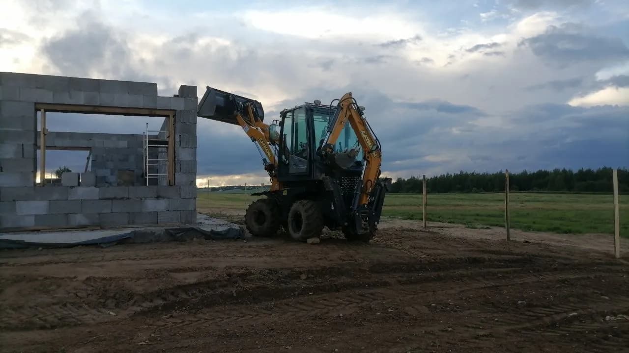 Мини-экскаватор-погрузчик CAT 504 на строительном объекте